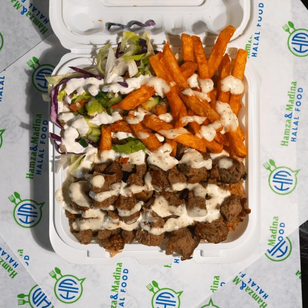 A white takeout container filled with Hamza & Madina Halal Food's gyro meat, fries, and salad.