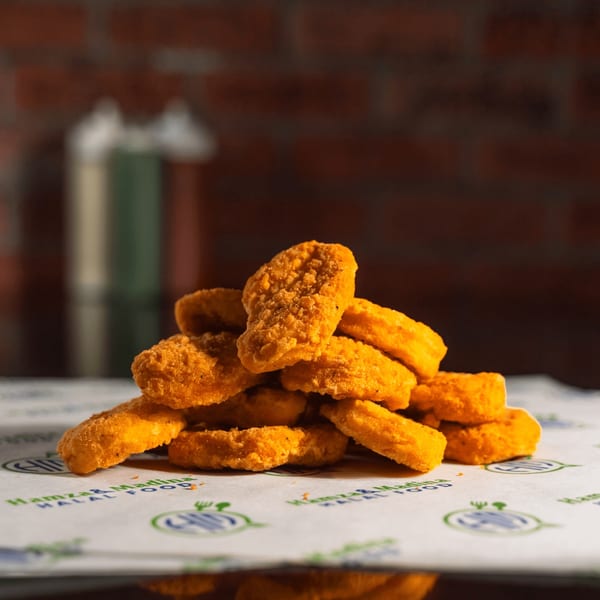 A pile of golden-brown chicken nuggets from Hamza & Madina Halal Food on branded paper.