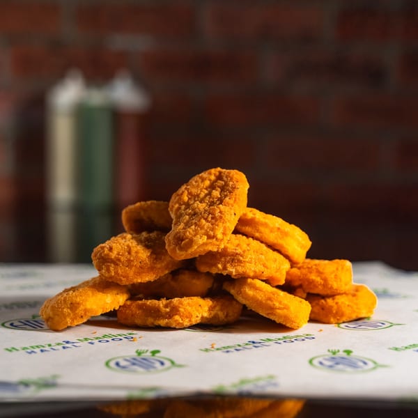 A pile of golden-brown Hamza & Madina Halal Food chicken nuggets on branded parchment paper.
